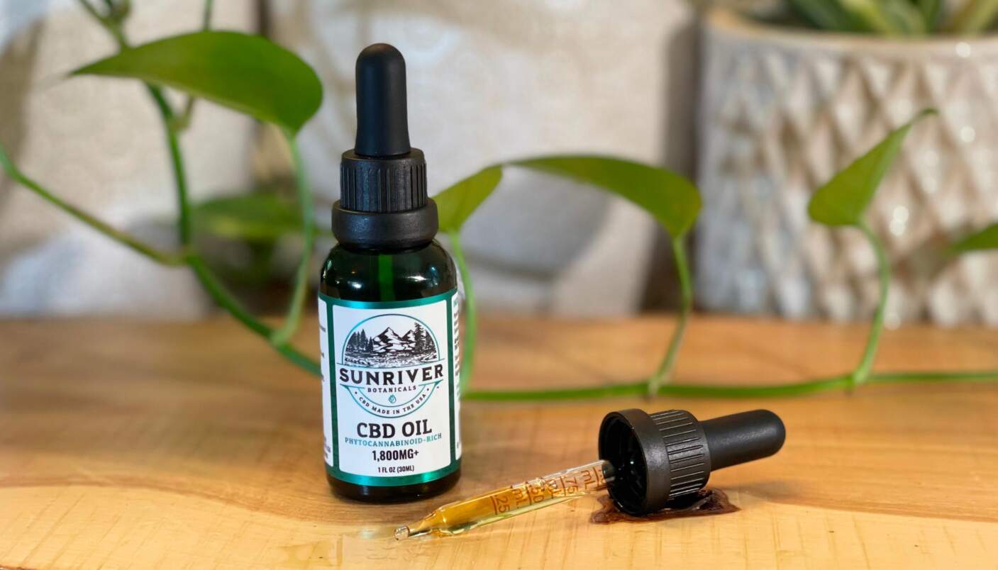 Bottle of Sunriver Botanicals' CBD oil on top a wooden desk