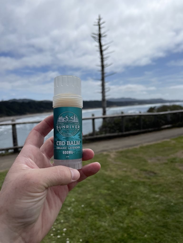 A hand holding up 600m of body balm for the body.